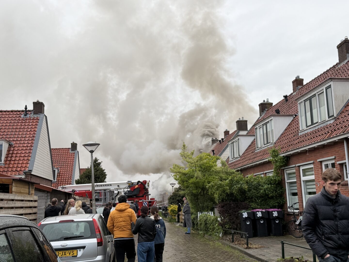 Grote uitslaande brand verwoest woning, bewoner gered via dakkapel