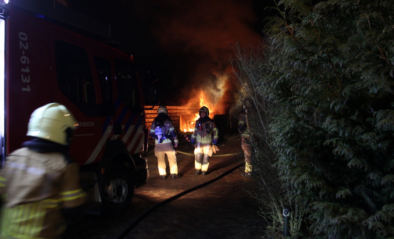 Bouwcontainer in lichterlaaie naast schutting