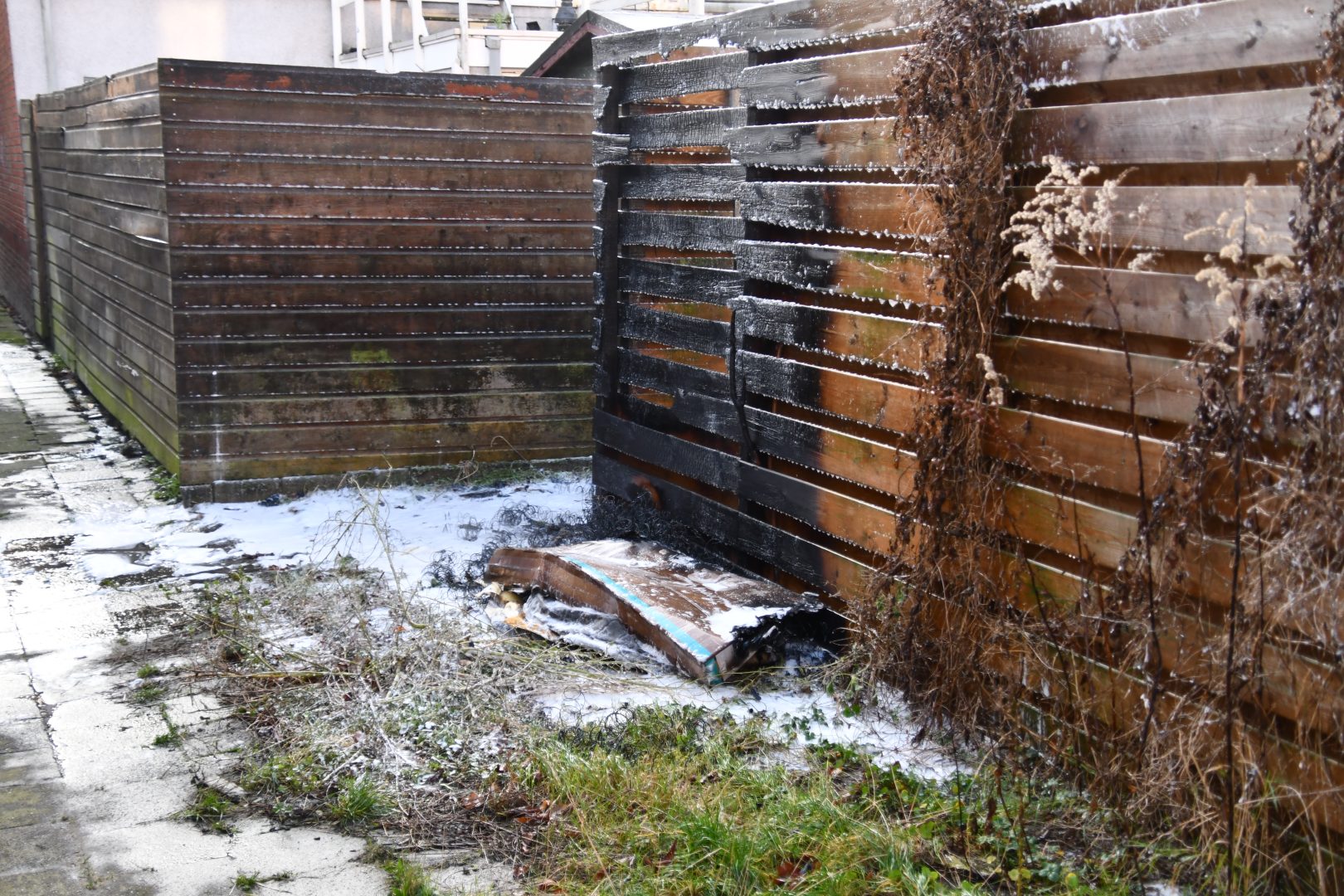 Grofvuil en schutting in brand