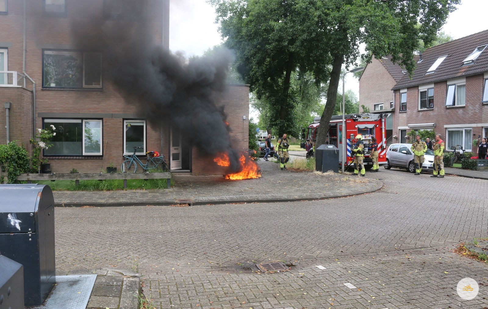 Scooter in brand tegen gevel van woning