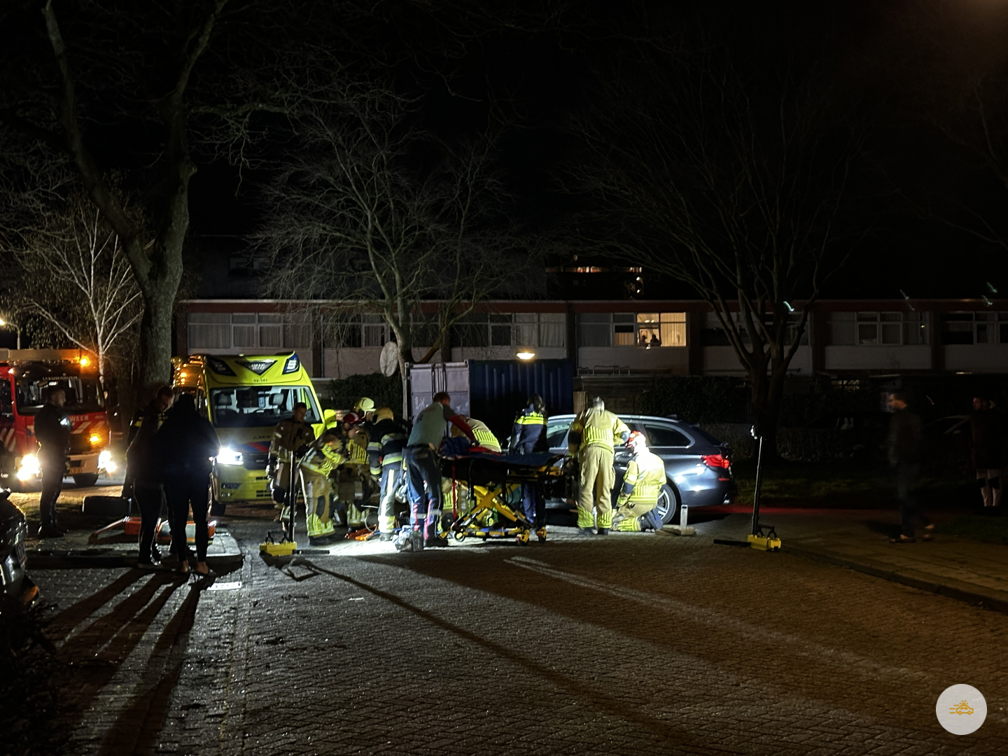 Persoon bekneld onder auto